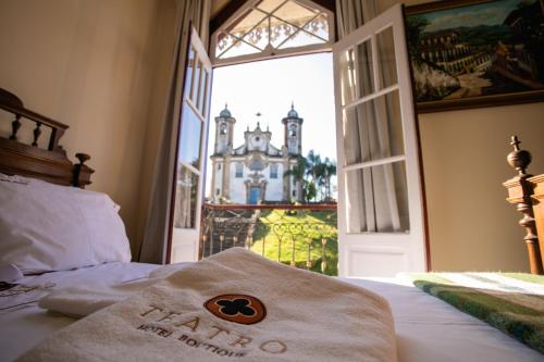um quarto de hotel com uma cama e uma janela aberta em Teatro Hotel Boutique em Ouro Preto