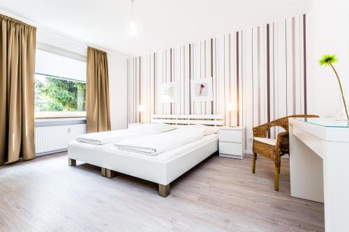 a white bedroom with a bed and a desk at Cityfair Apartments Köln in Cologne