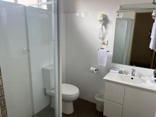 a bathroom with a toilet and a shower and a sink at Chelsea Motor Inn in Coffs Harbour