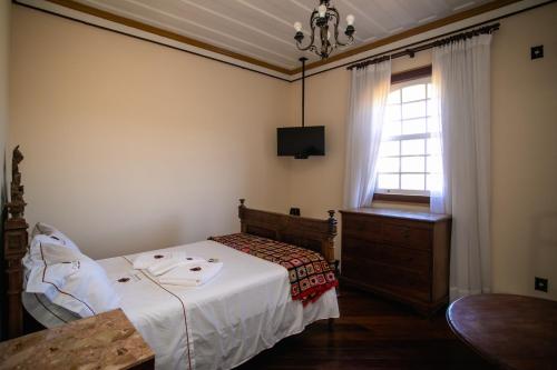 a bedroom with a bed and a dresser and a window at Teatro Hotel Boutique in Ouro Preto