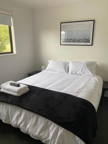1 dormitorio con 1 cama blanca grande con una foto en la pared en Sea Renity, en Safety Beach