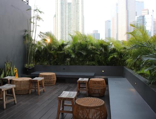 a patio with tables and wicker chairs in a building at La Boheme, Rooms and Coffee in Jakarta