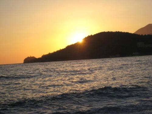 a sunset over a body of water with a hill at Magic Ionian Apartments & Rooms in Himare