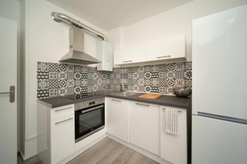 cocina con armarios blancos y fogones en Appartement tout équipé parking balcon 2 chambres, en Marsella
