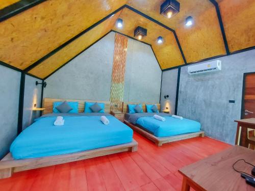 two beds in a room with blue sheets at SkyHome Wat JD I- Khai Resort & Restaurant in Ban Wat Boek
