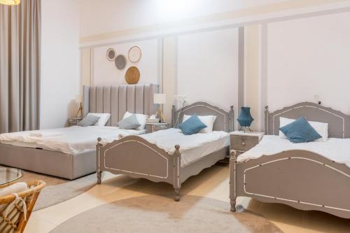 two beds in a room with two tables at Lazeemah Chalet استراحة اللزيمه in Ras al Khaimah