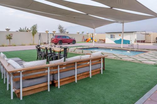 uma mesa e cadeiras sob um dossel branco ao lado de uma piscina em Lazeemah Chalet استراحة اللزيمه em Ras al-Khaimah