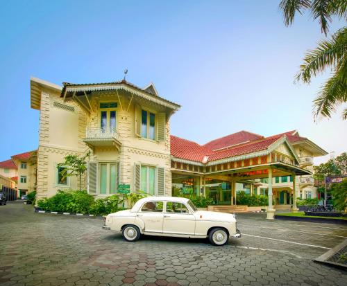 a white car parked in front of a building at The Phoenix Hotel Yogyakarta - MGallery Collection in Yogyakarta