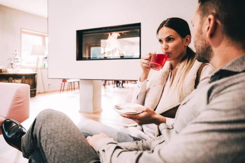 a man and woman sitting on a couch drinking wine at Kinderhotel Stegerhof in Donnersbachwald