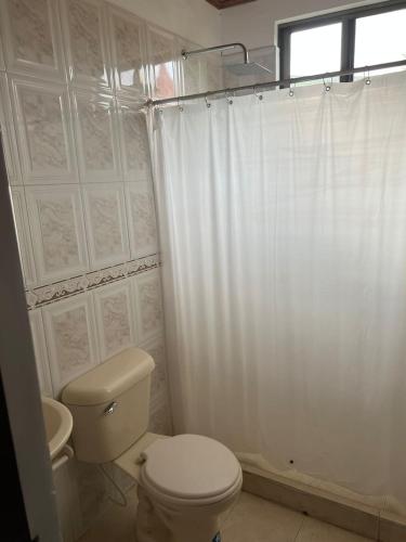 a bathroom with a toilet and a shower curtain at Villa Tarek in Carmen de Apicalá