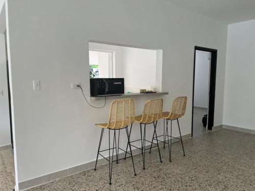 a kitchen with three bar stools and a counter at Villa Tarek in Carmen de Apicalá