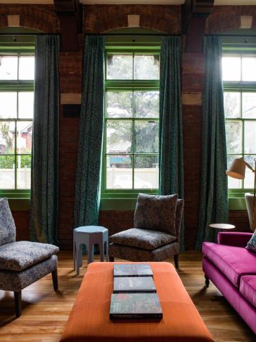 a living room with a couch and chairs and windows at The Observatory Hotel Christchurch in Christchurch