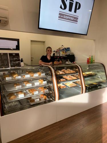 a woman standing behind a bakery display case with pastries at Mia Mia House in the Desert in Newman