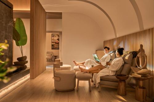 two people sitting on a couch in a living room at Holiday Inn Resort Ho Tram Beach by IHG in Ho Tram