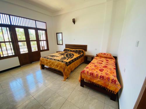 a bedroom with two beds and a window at La Polena in Matara