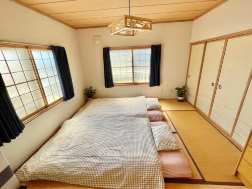 two beds in a room with windows at Holiday House Toya in Lake Toya