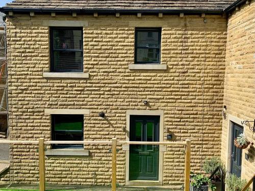 a brick building with a green door and windows at Victoria House in Holmfirth