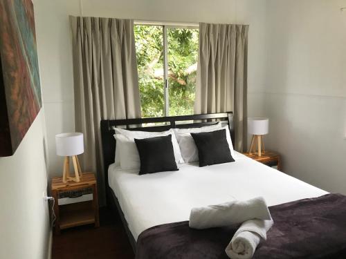 a bedroom with a white bed with two lamps and a window at Ocean Breeze Units in Bowen