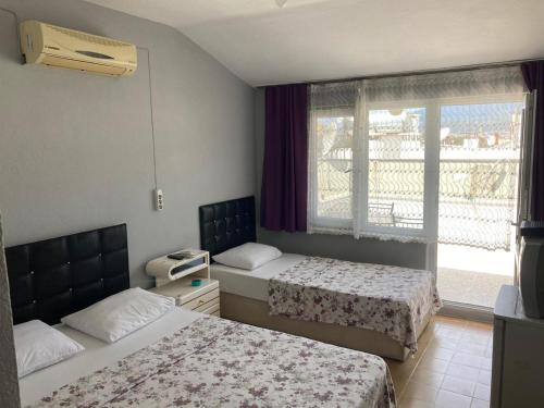 a hotel room with two beds and a window at Set Arat Motel & Pansiyon in Akçay
