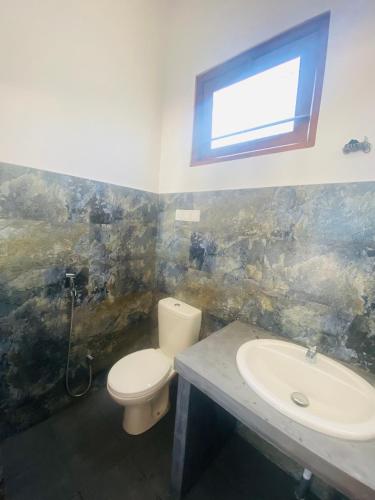 a bathroom with a toilet and a sink and a window at La Polena in Matara