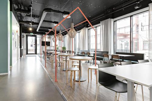 a row of tables and chairs in a room with windows at Forenom Hotel Kista in Stockholm