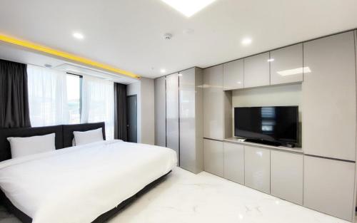 a bedroom with a white bed and a flat screen tv at Songjeong Blue Castle Hotel in Busan