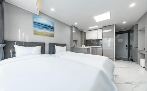a bedroom with a large white bed and a kitchen at Songjeong Blue Castle Hotel in Busan