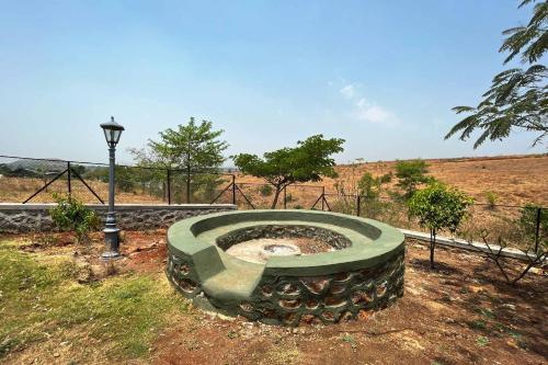 a stone bench in a field with a street light at Stone House Bezze by StayVista with Lake view, Jacuzzi & Lawn - your perfect getaway in Nashik