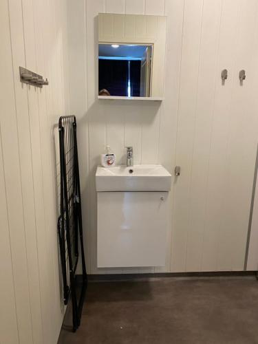 ein weißes Badezimmer mit einem Waschbecken und einem Spiegel in der Unterkunft Mosjøen Overnatting, Tordenskjolds gate 24b in Mosjøen