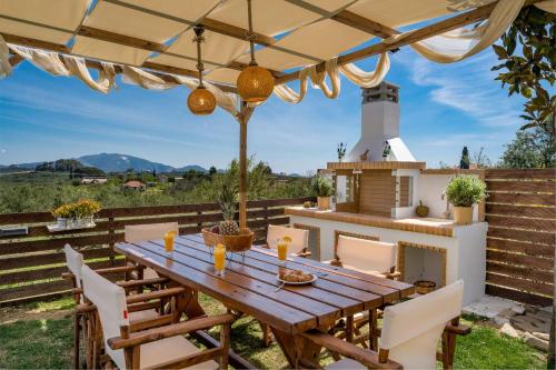 a wooden table and chairs on a patio with a fireplace at Magnolia Homes Zakynthos in Zakynthos