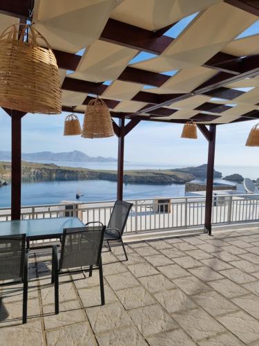 a patio with a table and chairs and a view of the water at Soultana studios in Líndos