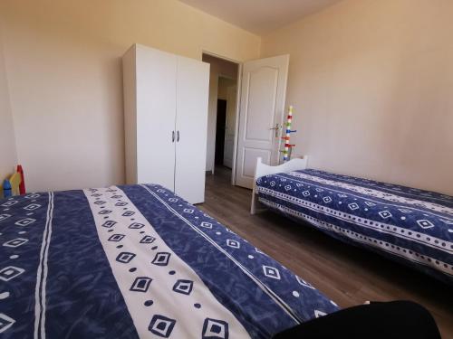 une chambre avec deux lits avec des draps bleus et blancs dans l'établissement Petite maisonnette de plein pied, à Le Taillan-Médoc