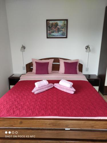 a large bed with red sheets and two towels at Vila Čair DOPLATA ZA BAZEN in Soko Banja