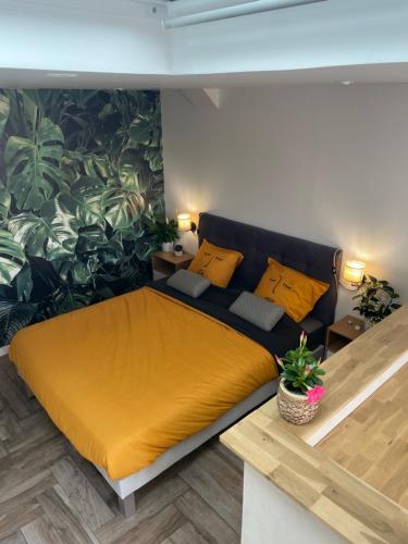 - une chambre dotée d'un lit avec des draps jaunes et une plante dans l'établissement Le Studio de l'Olivier, à Courcelles-sur-Seine