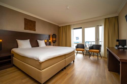 een hotelkamer met een bed, een bureau en stoelen bij Fletcher Hotel-Restaurant Arion-Vlissingen in Vlissingen