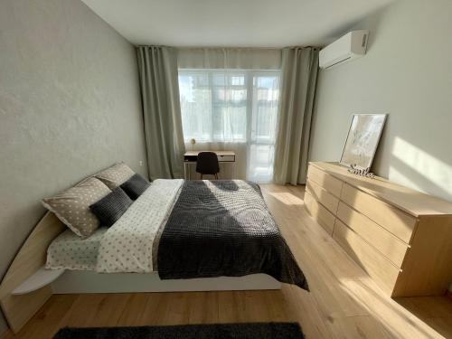 a bedroom with a bed and a desk and a window at Comfy & Stylish in Varna City