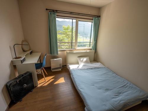 a small bedroom with a bed and a window at Five Peaks Jigokudani in Shiga Kogen