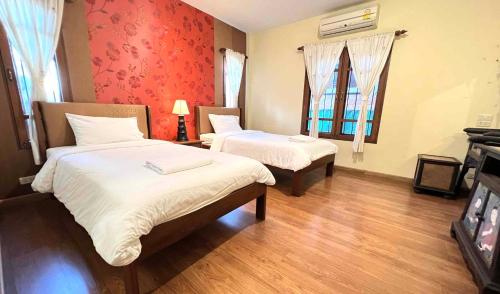 una camera d'albergo con due letti e una finestra di Plumeriahome near Walking Street a Chiang Mai