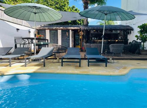 um pátio com cadeiras e guarda-sóis ao lado de uma piscina em Guest House et Restaurant Sous le Badamier em Grand Baie
