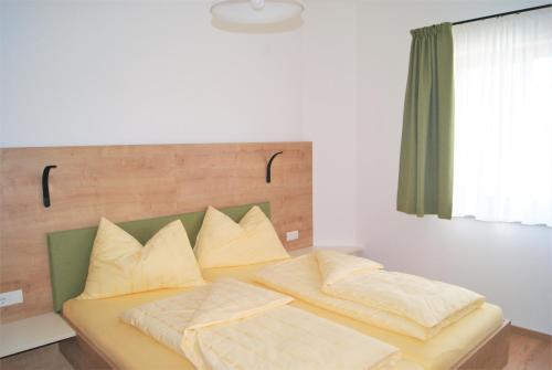 1 dormitorio con 1 cama con 2 almohadas en Rollstuhlfreundliche Ferienwohnung in ruhiger Lage- Panorama Terrasse, 2 SZ, en Pöllauberg