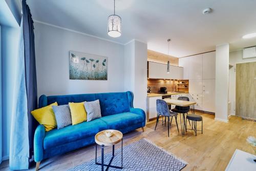 een woonkamer met een blauwe bank en een tafel bij LAGUNA Apartament Polanica Residence 38 in Polanica-Zdrój