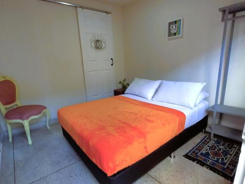 a bedroom with a bed with an orange blanket and a door at Casa Azul Boutique Hostel in Pereira