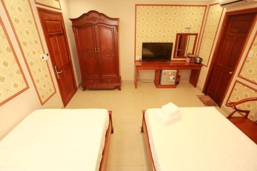 a room with two beds and a tv and a desk at THANH TAI HOTEl 1 in Ho Chi Minh City
