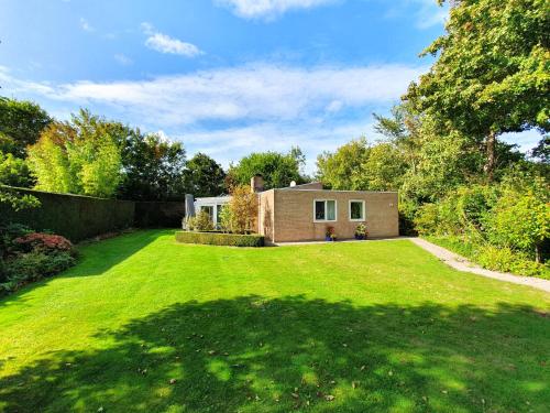 a house in a yard with a green lawn at Wunderschönes Ferienhaus in Strandnähe in Retranchement