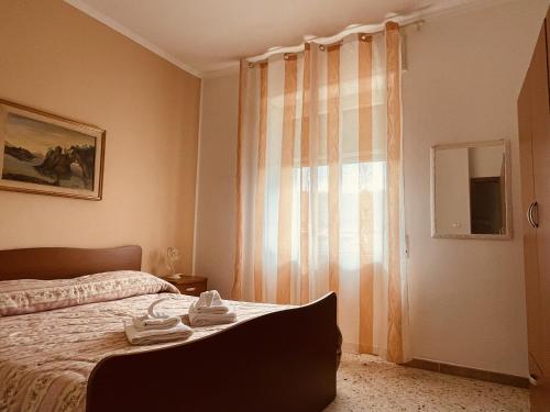 a bedroom with a bed and a window with towels on it at Nausicaa Beach and Town in Agropoli