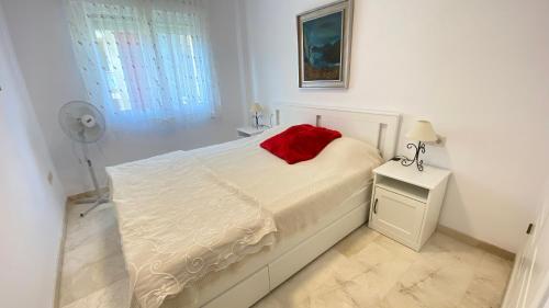 Un dormitorio con una cama con una almohada roja. en Cascada de las Marinas, en Denia