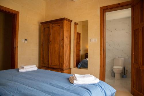 a bedroom with a blue bed and a toilet at Ta' Martinu in Sannat