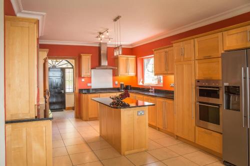 a kitchen with orange walls and wooden cabinets at Once Upon a Tide in Clifden
