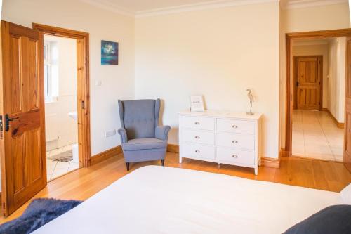 a bedroom with a bed and a chair and a dresser at Once Upon a Tide in Clifden