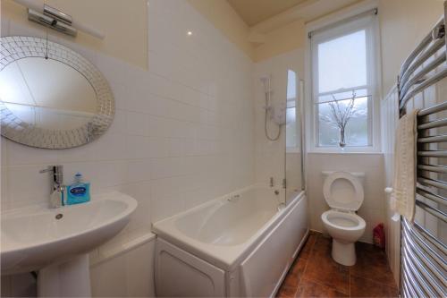 een badkamer met een bad, een wastafel en een toilet bij Argyll Mansions in Oban